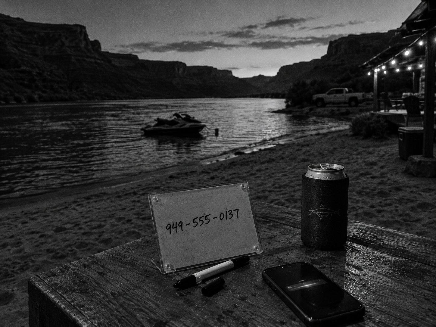 A glass ink board with handwritten digits, a marker and a phone by the river at dusk